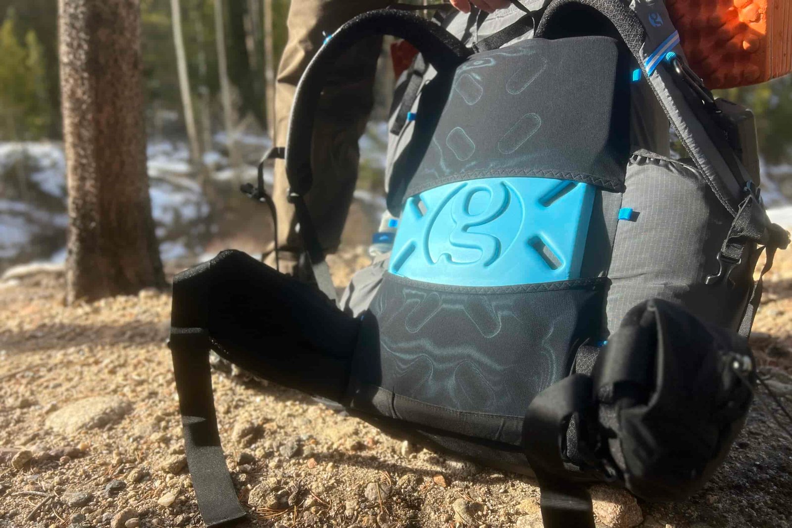 A view of the back panel of the Mariposa 60 with its removable sit pad. A snowy forest is in the background.