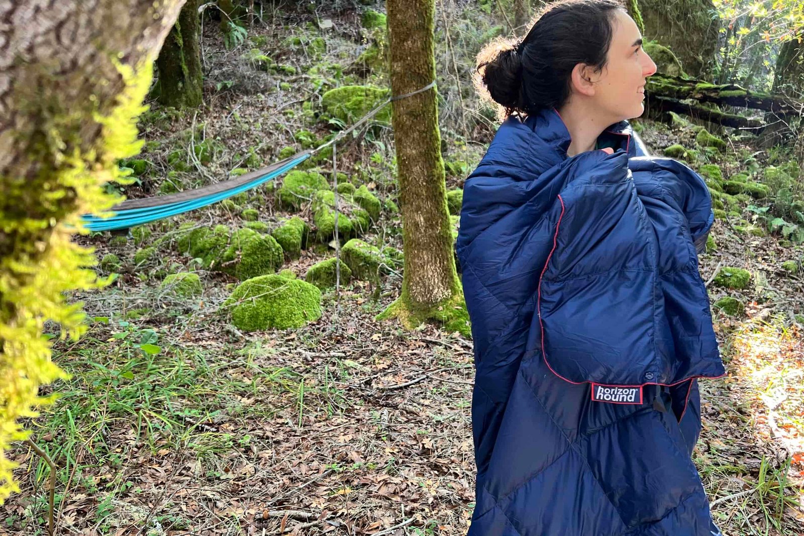 Person standing in the woods wrapped in the Horizon Hound Trek Blanket.