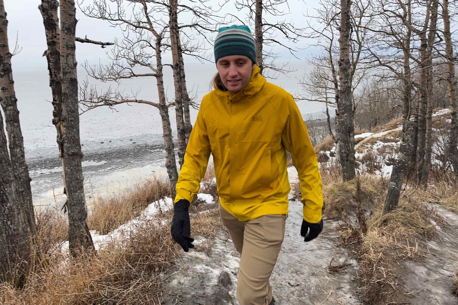 A man walks down an icy trail on a rainy day.