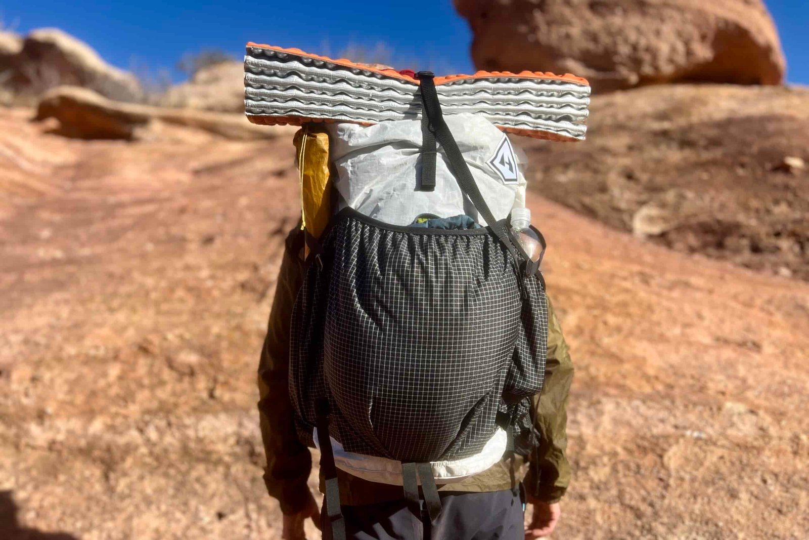 A back view of a hiker wearing the Southwest 55 pack with a desert background.