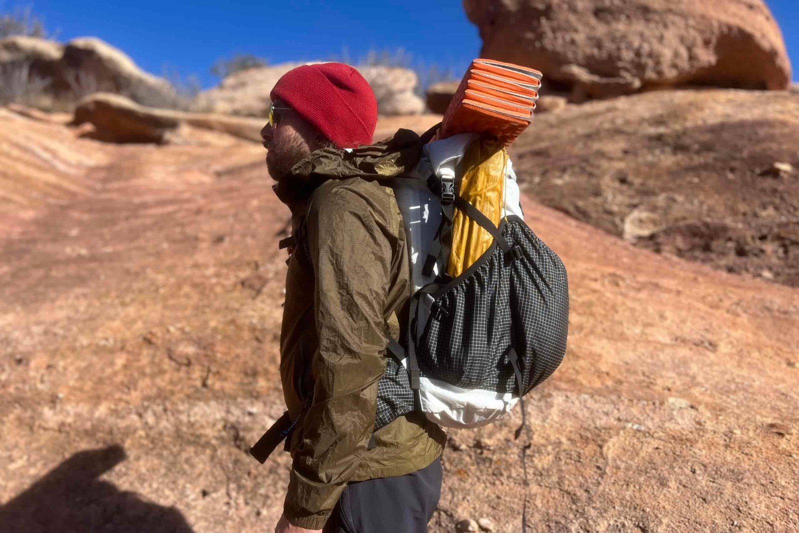A profile view of a hiker wearing a fully loaded Southwest 55 pack with a desert background.
