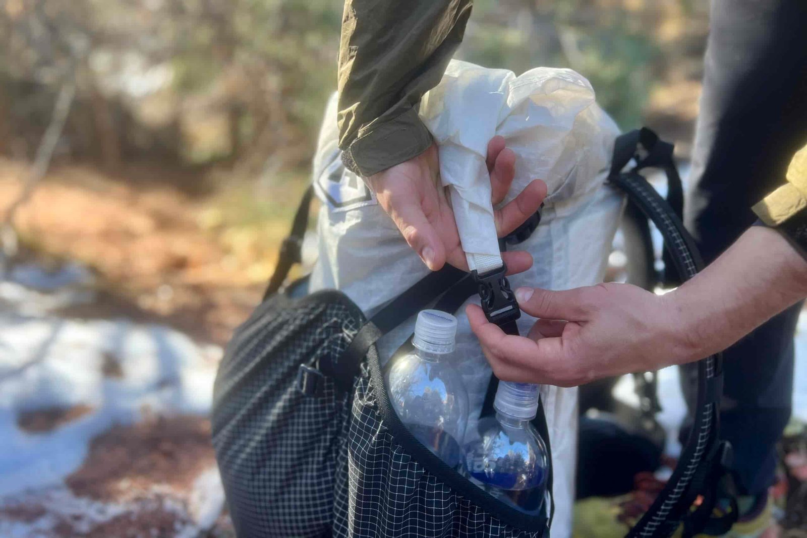 A hiker shows the roll-top buckle on the Southwest 55 with a snowy desert background.