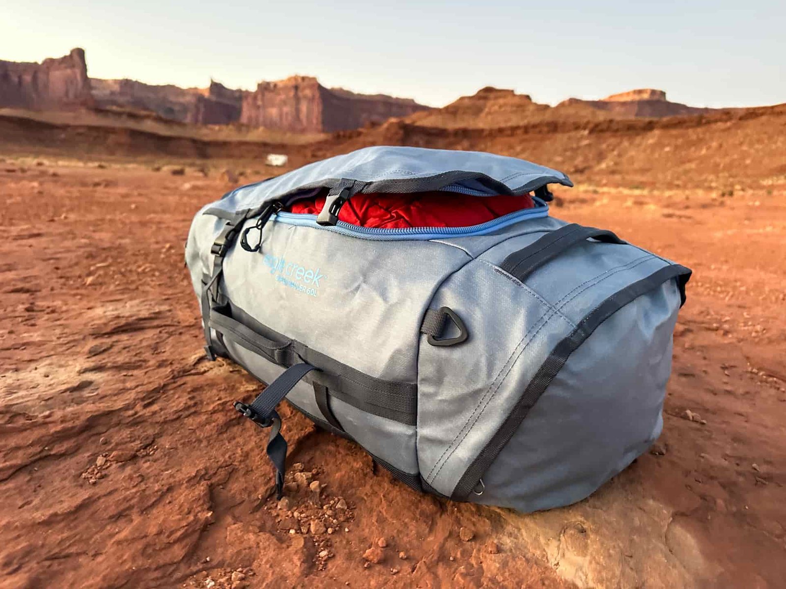 The Eagle Creek Cargo Hauler 60L duffel slightly open and sitting stuffed full in the desert.