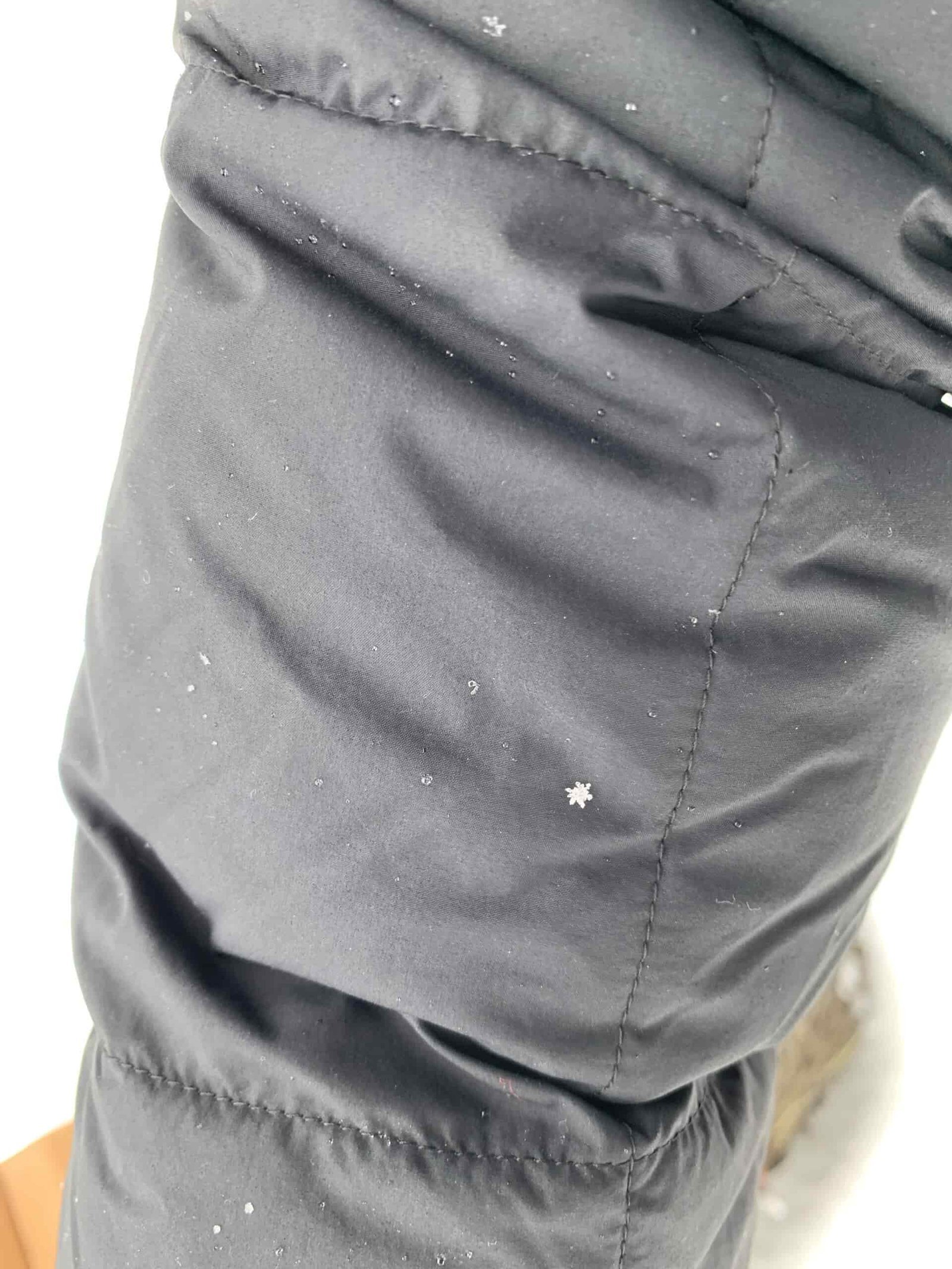 a close up of a snowflake and melted snow water droplets on the outdoor research coze down parka
