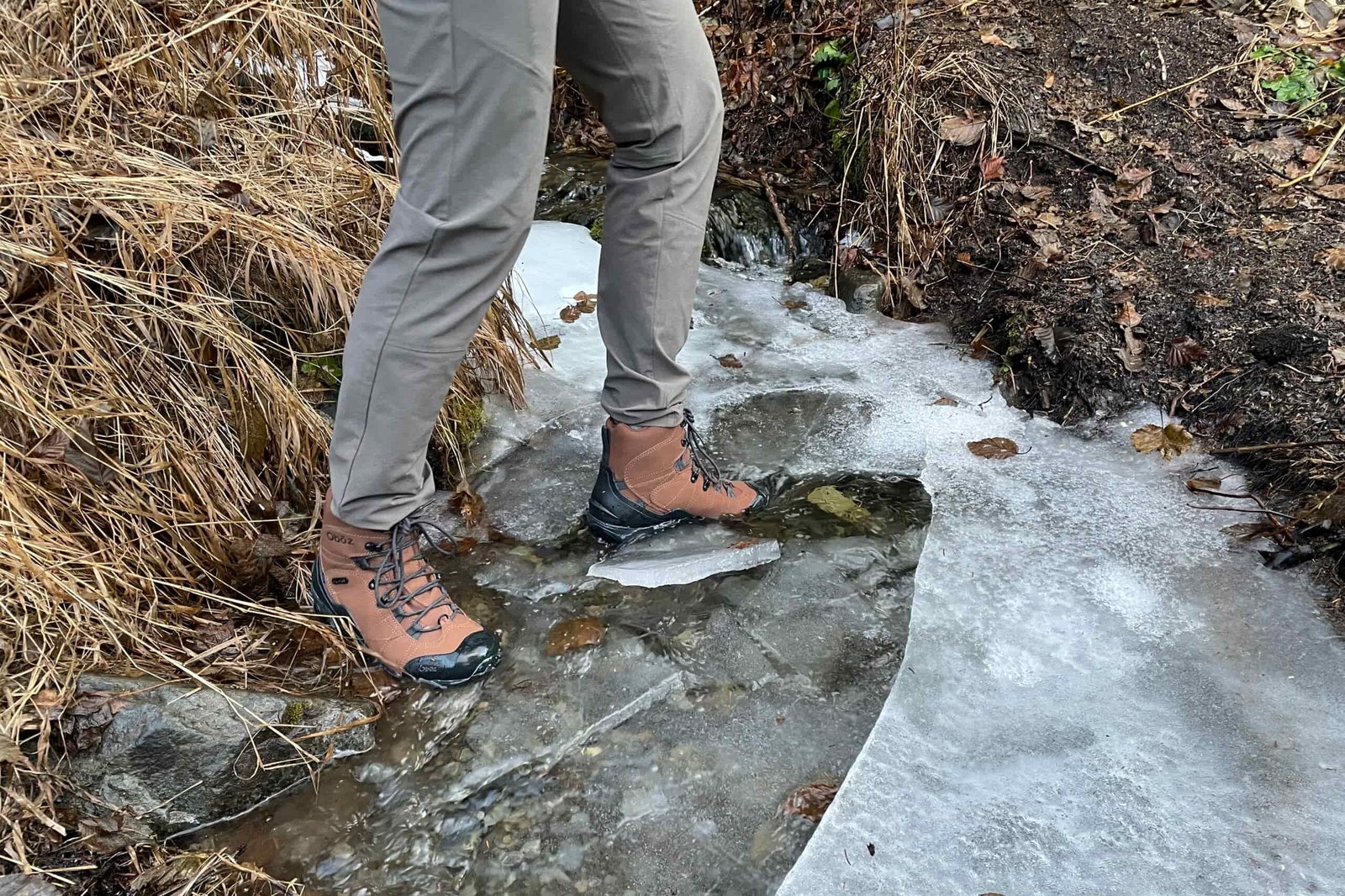 A closeup of boots submerged in an icy creek.