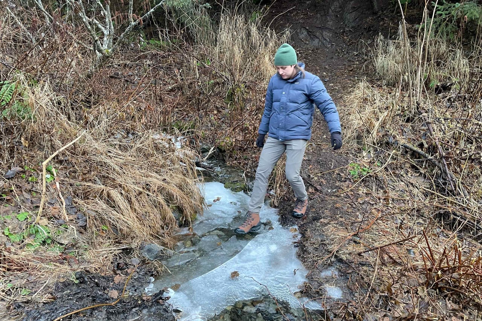 A man crosses an ice covered creek.