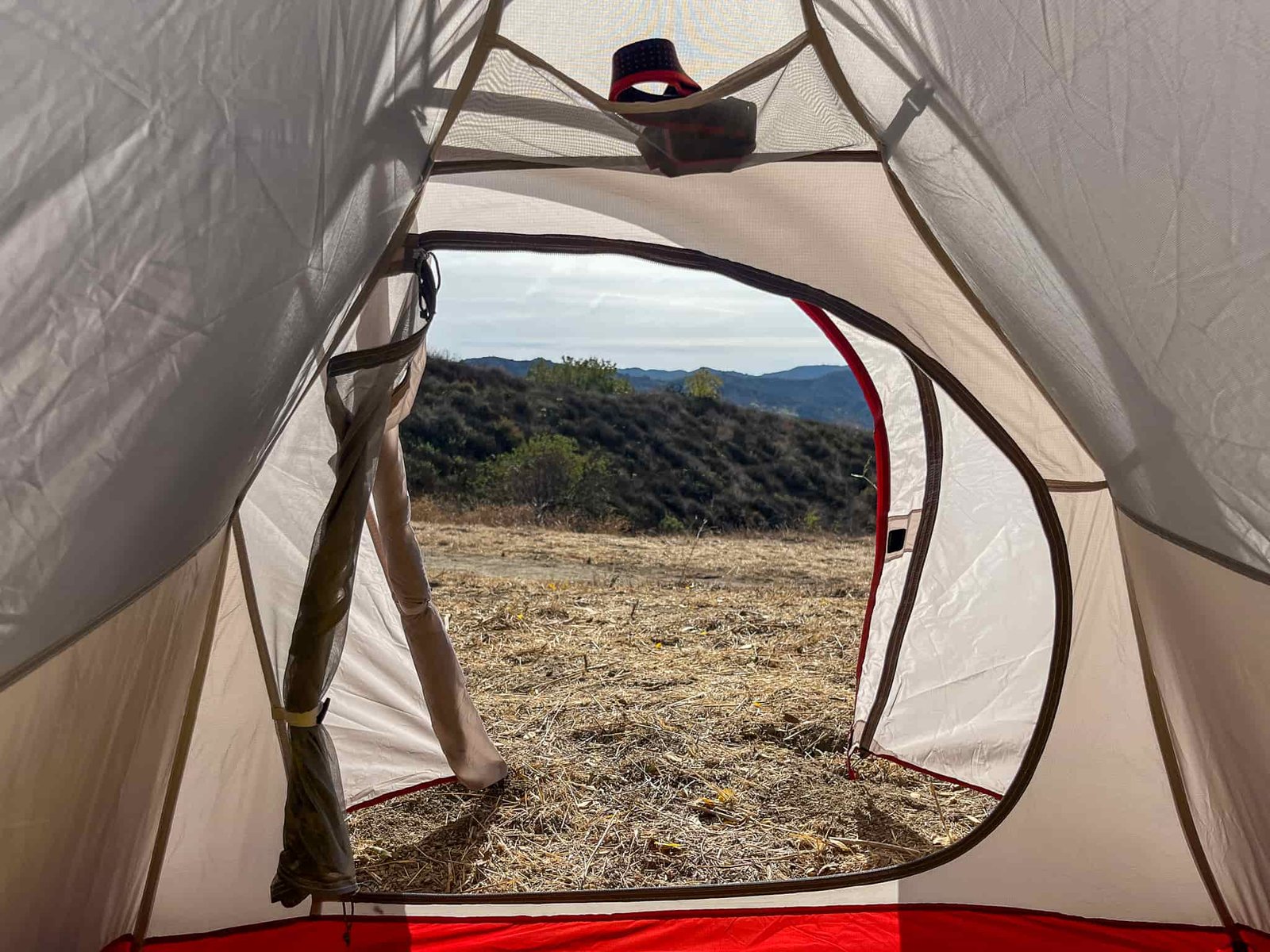 A view of rolling hills and distant mountains through the open doorway of Naturehike CloudUp 2, showcasing the tent's entryway and gear storage options.