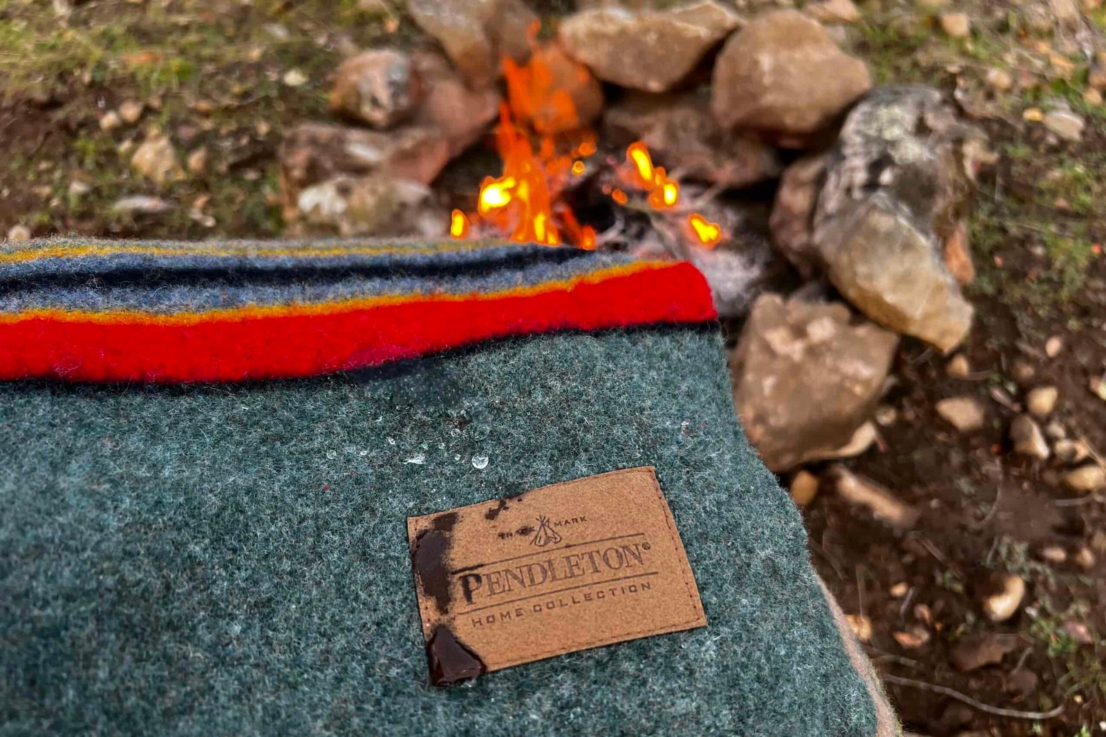 Close-up of the Pendleton Yakima Camp Blanket held over a small campfire, showing how water absorbs into the fabric.