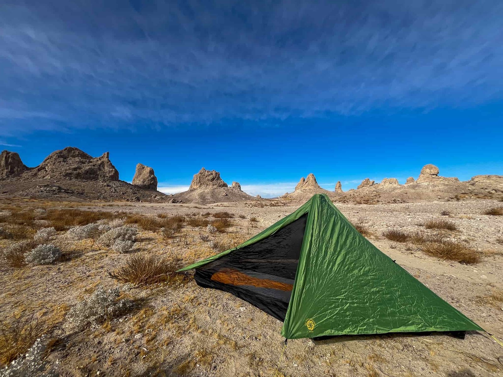 Side view of the Six Moon Designs Skyscape Scout showing the open portion of the canopy, revealing the inner mesh and sleeping bag inside. Desert rock pinnacles and blue sky in the background.