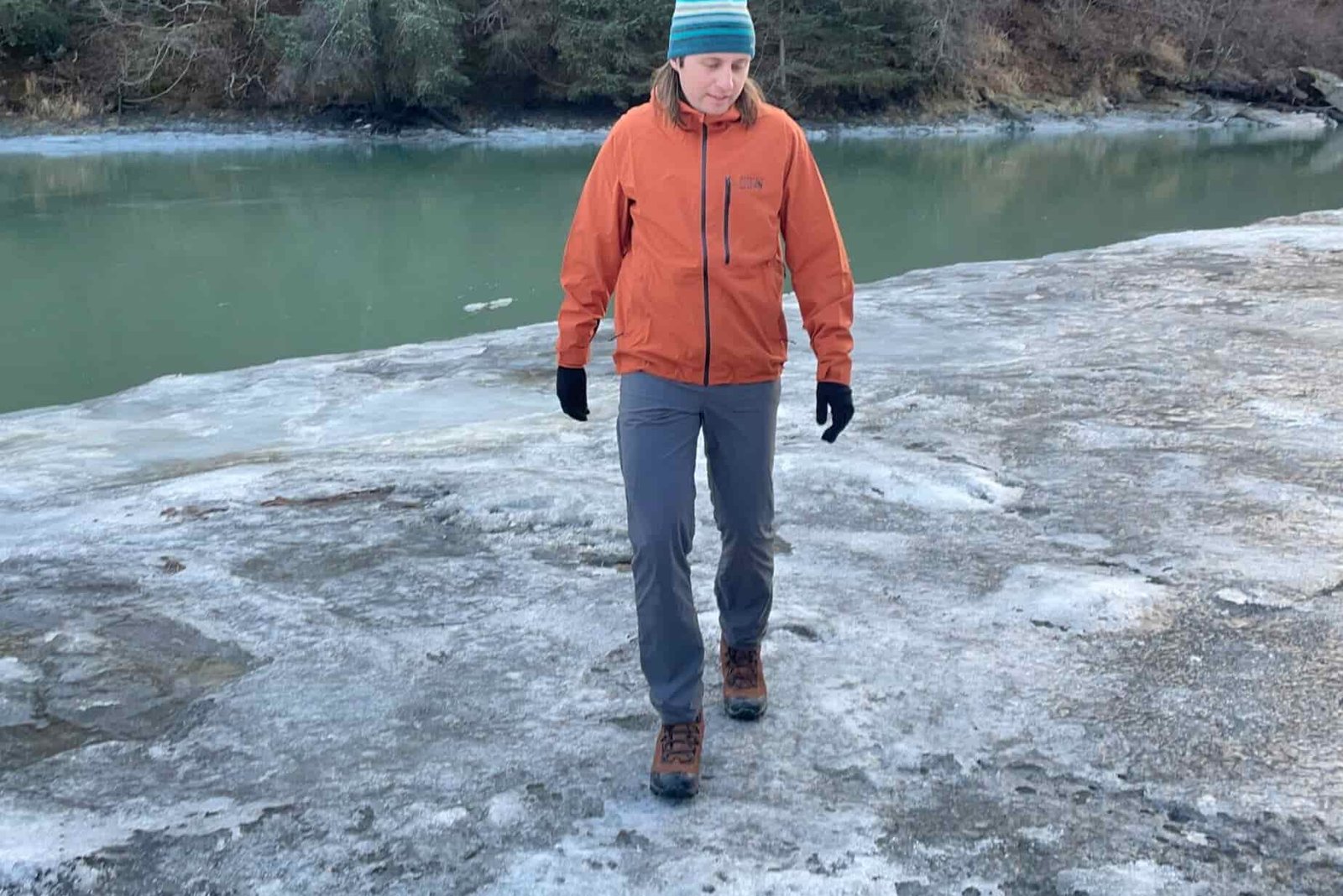 A man hikes along the icy banks of a river.