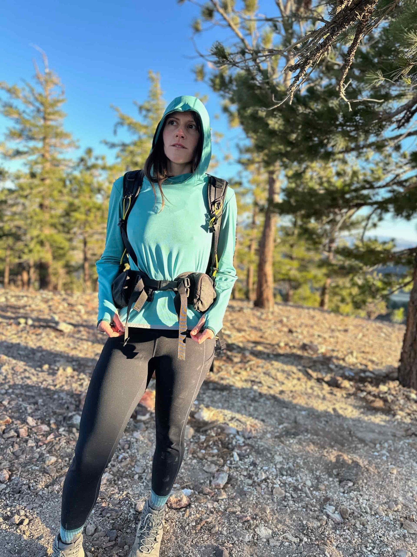 woman hiking with backpacking pack through pine forest
