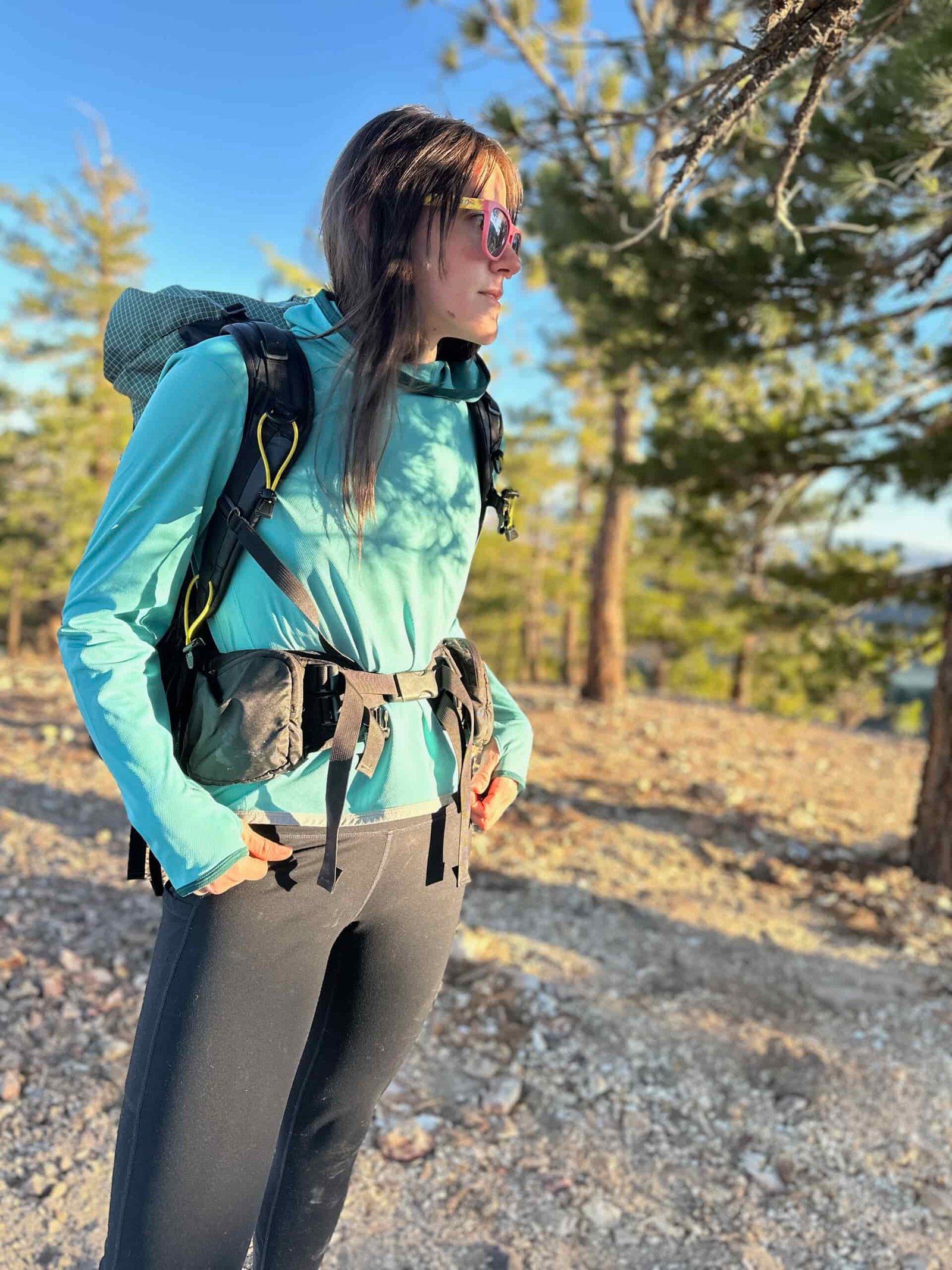 woman hiking with backpacking pack through pine forest