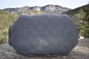 Close up of the Klymit LUXE pillow fully inflated with mountains blurred in the background