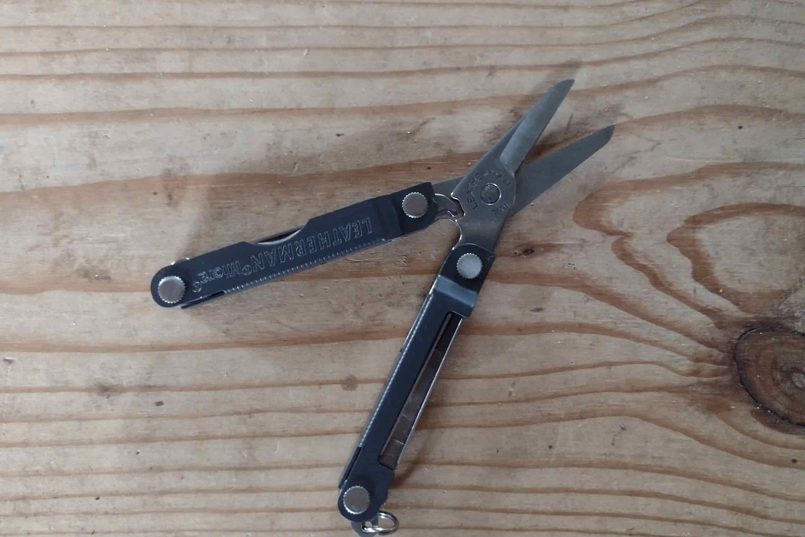 The Leatherman Micra with its scissors open, resting on a board.