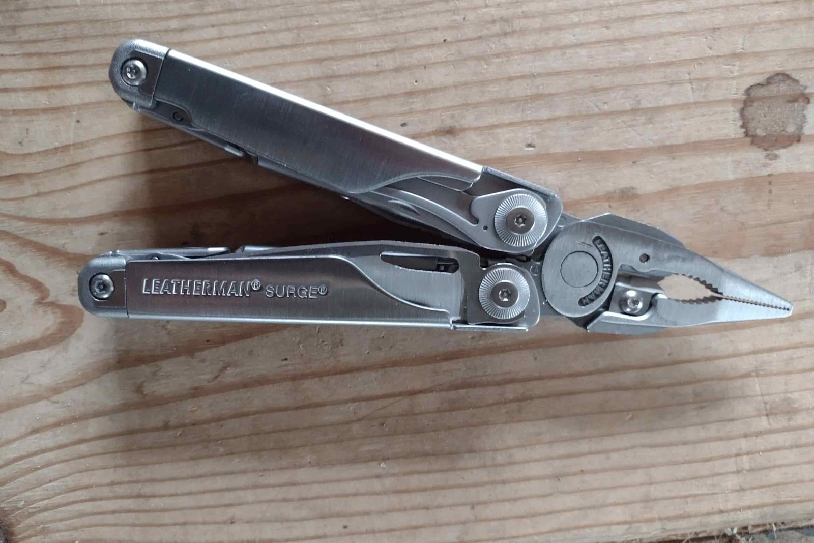 The silver Leatherman Surge resting on a board, with its needle nose pliers extended.