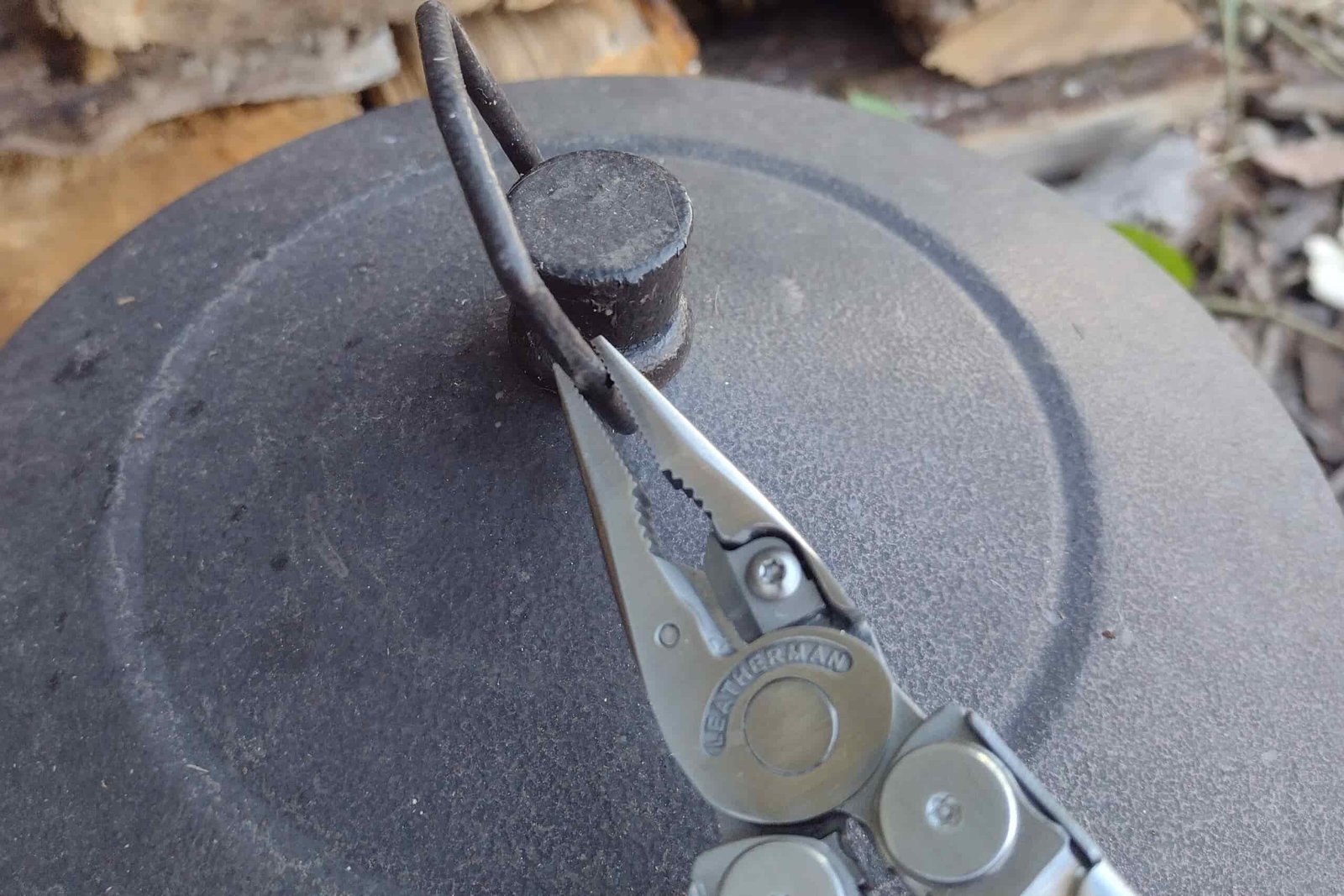 The Leatherman Wave+ gripping a metal cover handle outside.