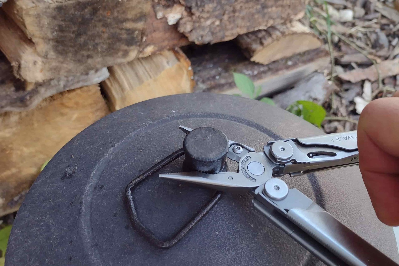 The Leatherman Wave+ gripping a metal cover with its needle-nose pliers.