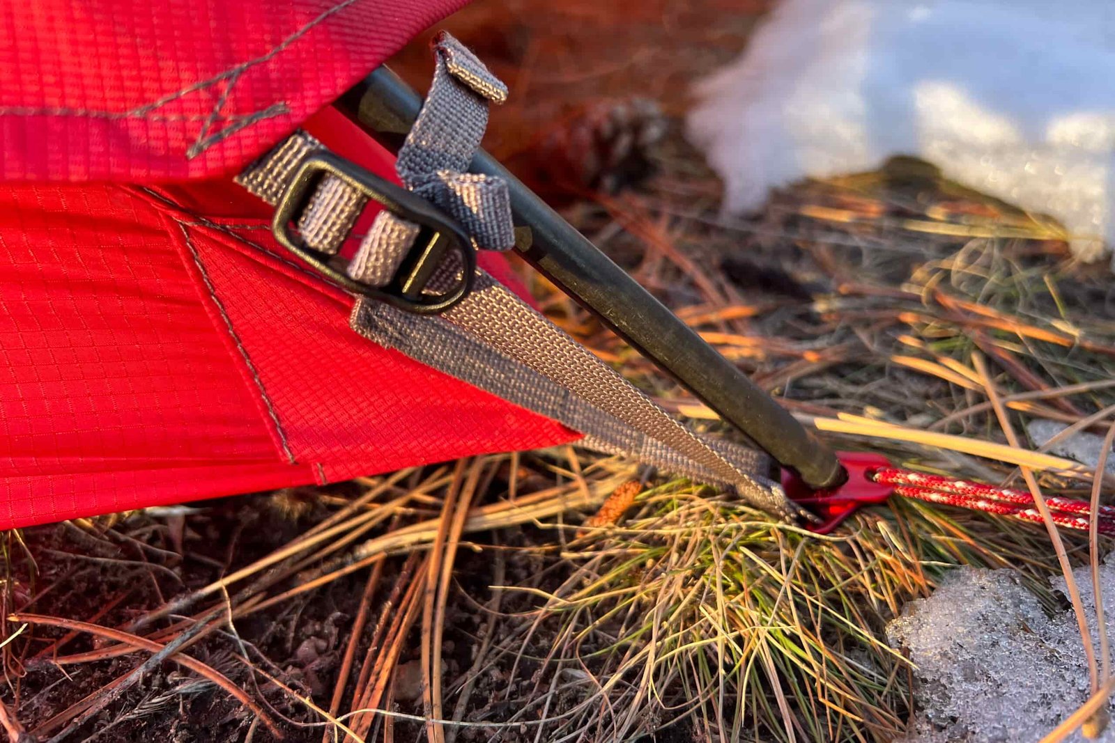 Close-up of the MSR Access 2 tent’s stake system secured in the snow.