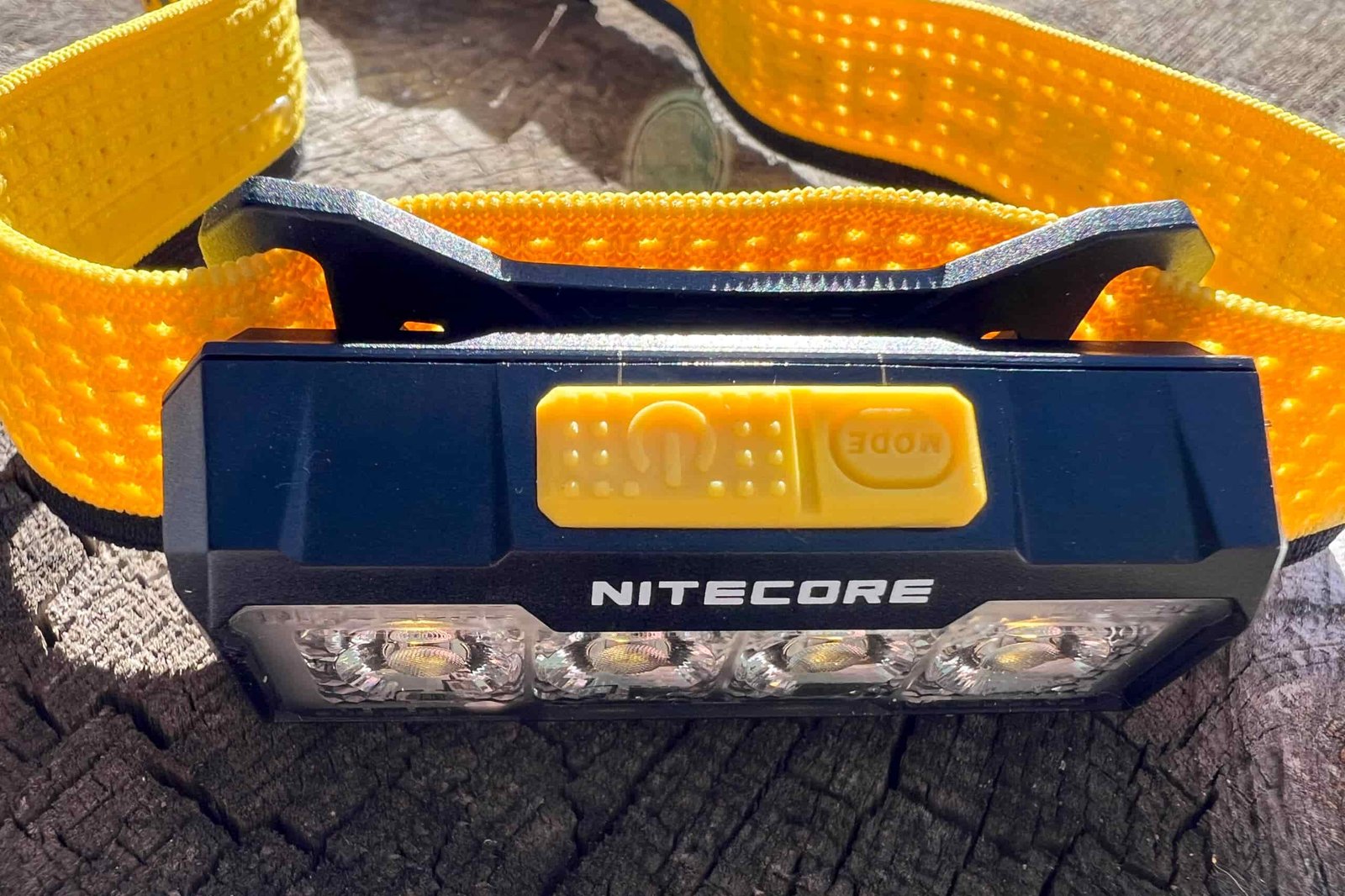 The photo features a Nitecore NU27 headlamp sitting on a log. The photo is taken from above.