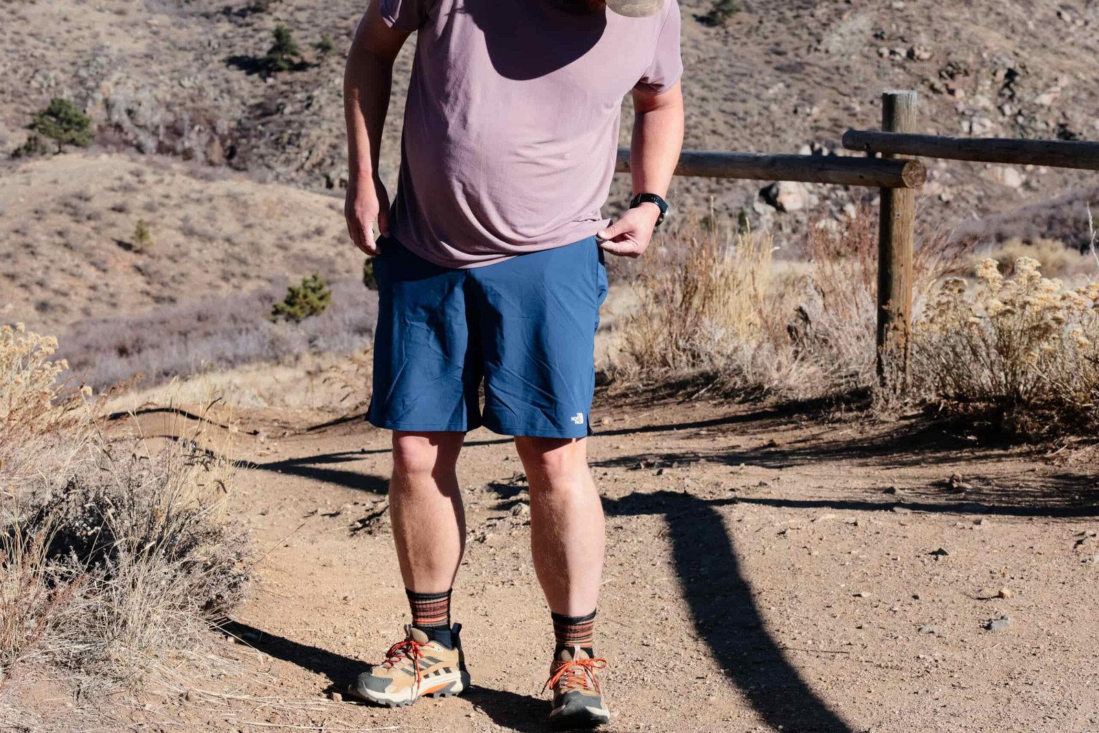 Man opening back pocket on a hiking trail.