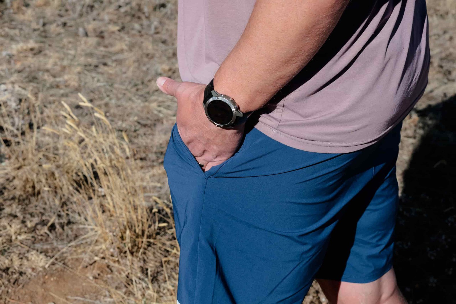 A hand in a pocket of blue shorts.