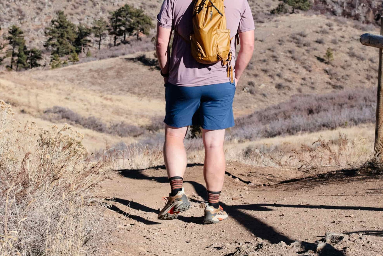 Man in blue shorts hikes away on a trail.