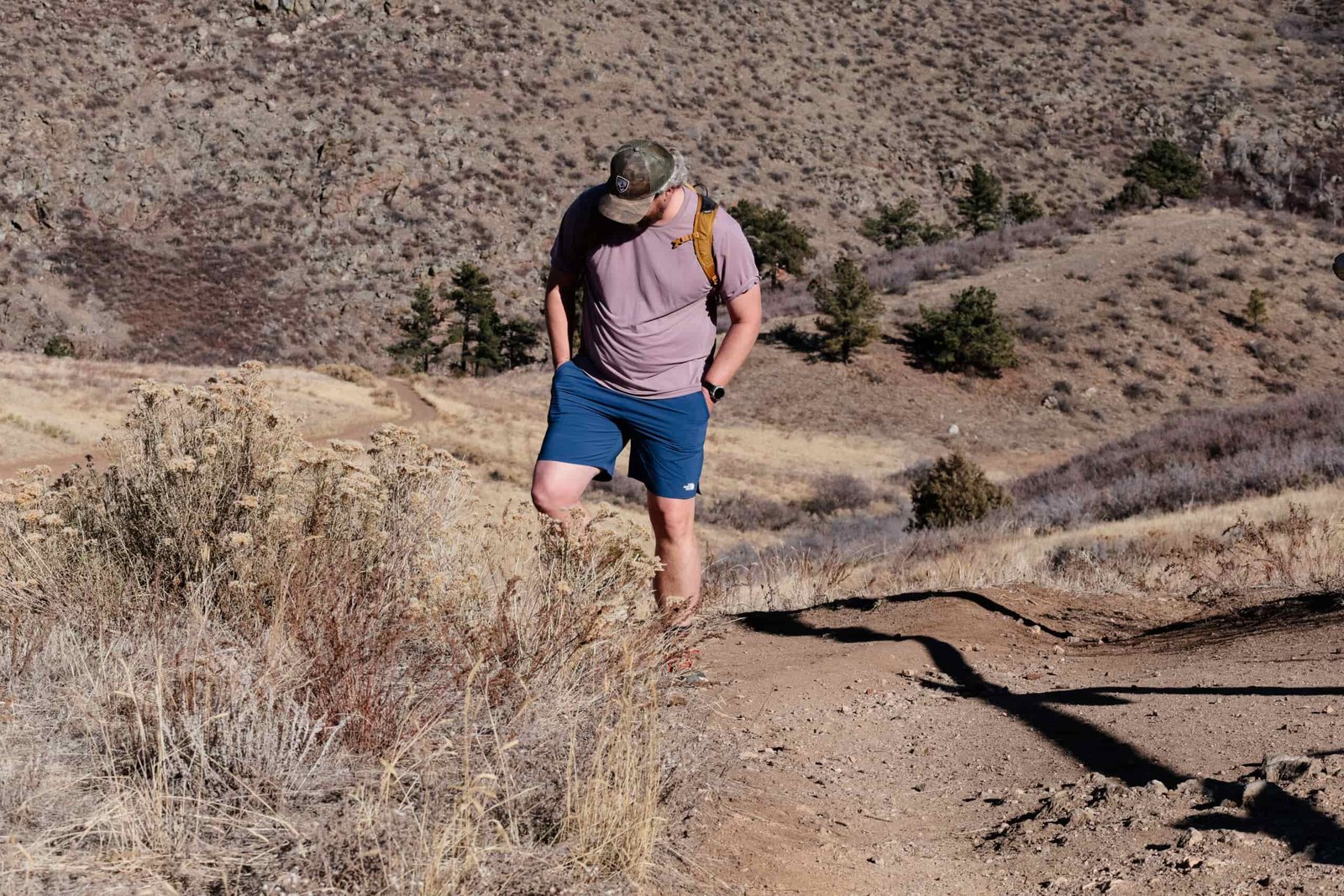 A man hiking on a mountain trail in shorts and a t-shirt.