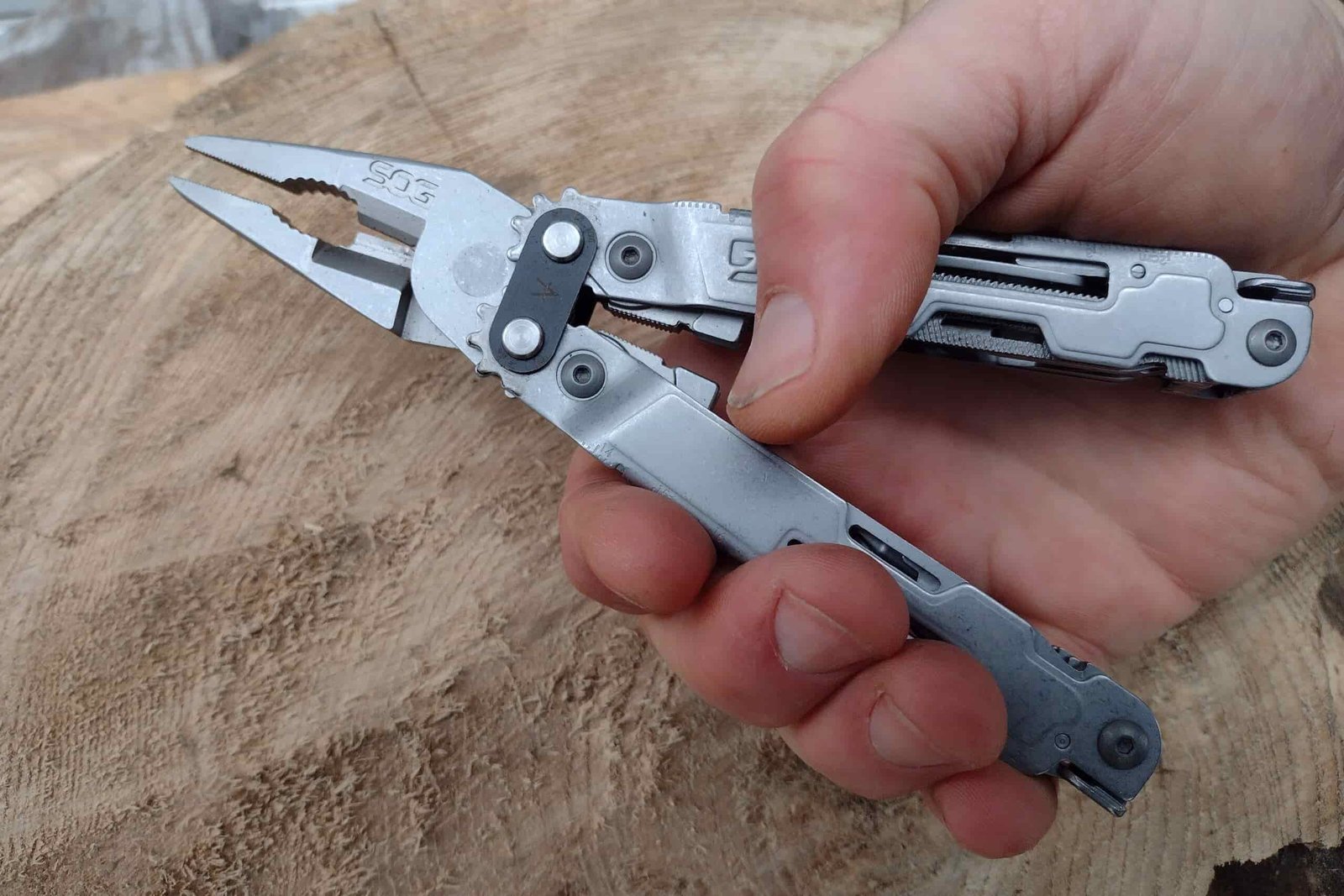 The SOG PowerAccess Deluxe held in hand above a log.