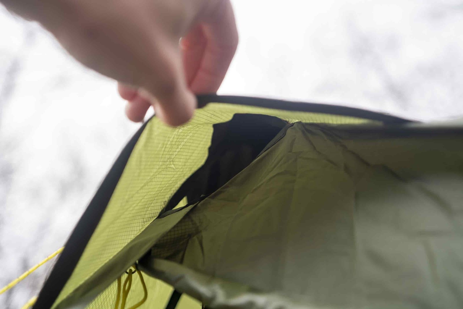 a hand holds open a tent vent