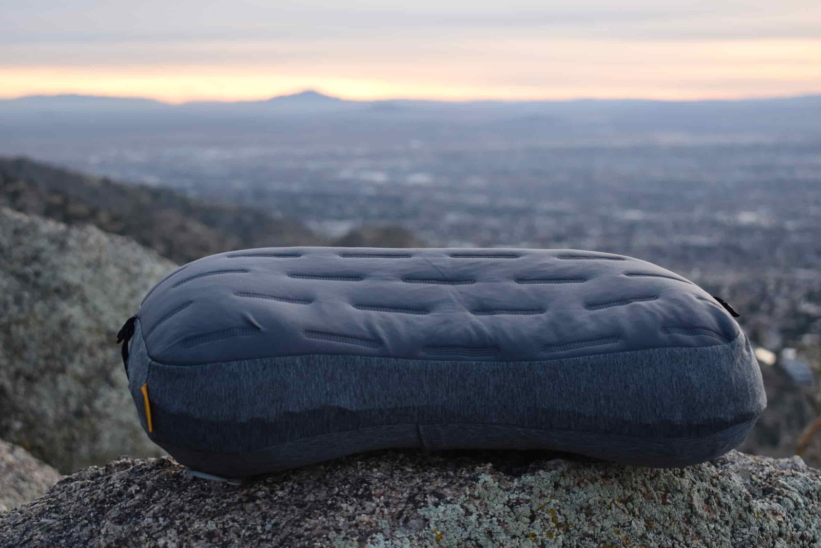 Trekology camp pillow lying on a boulder with a volcanic horizon in the background
