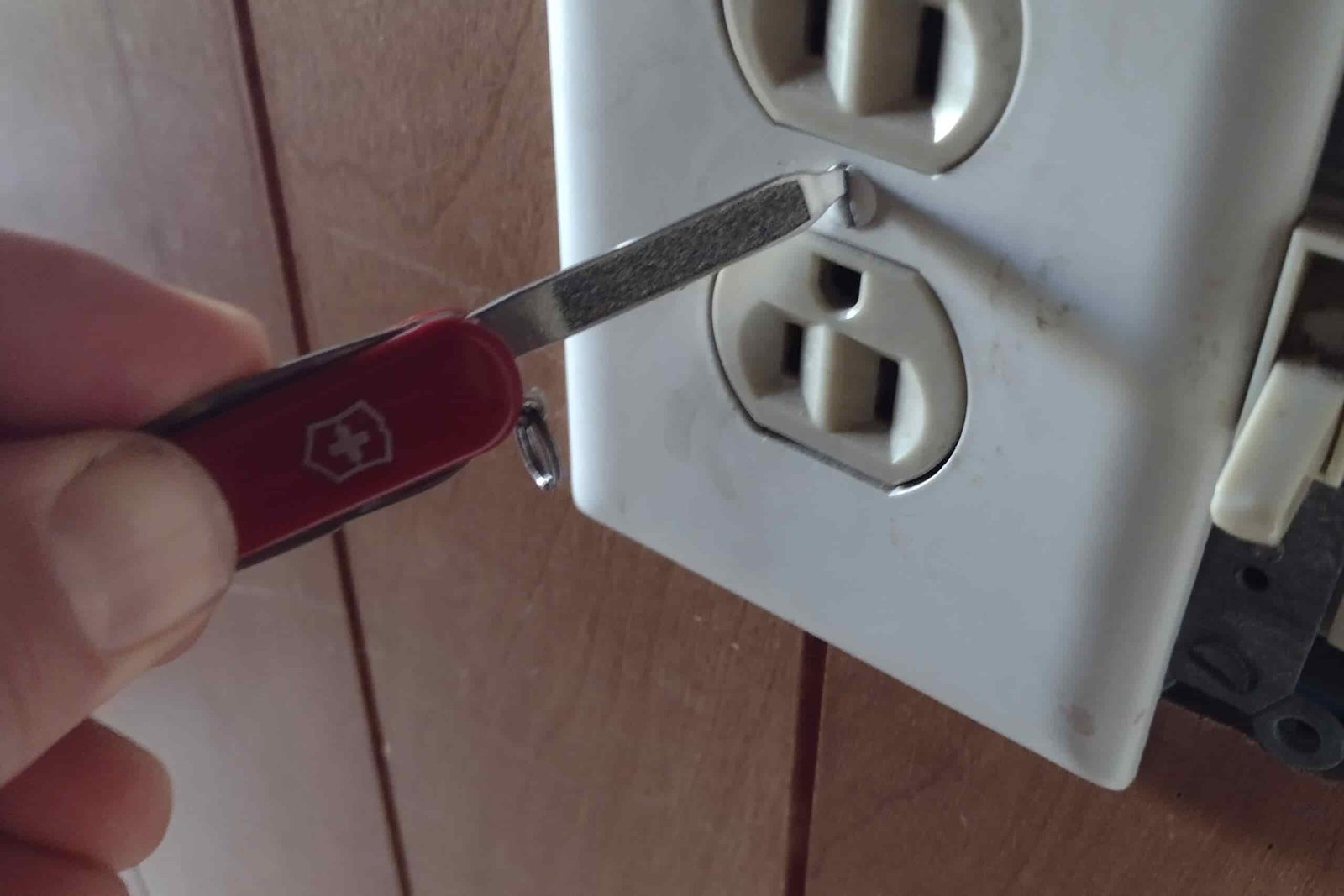 The Victorinox Classic SD screwing in an outlet cover.