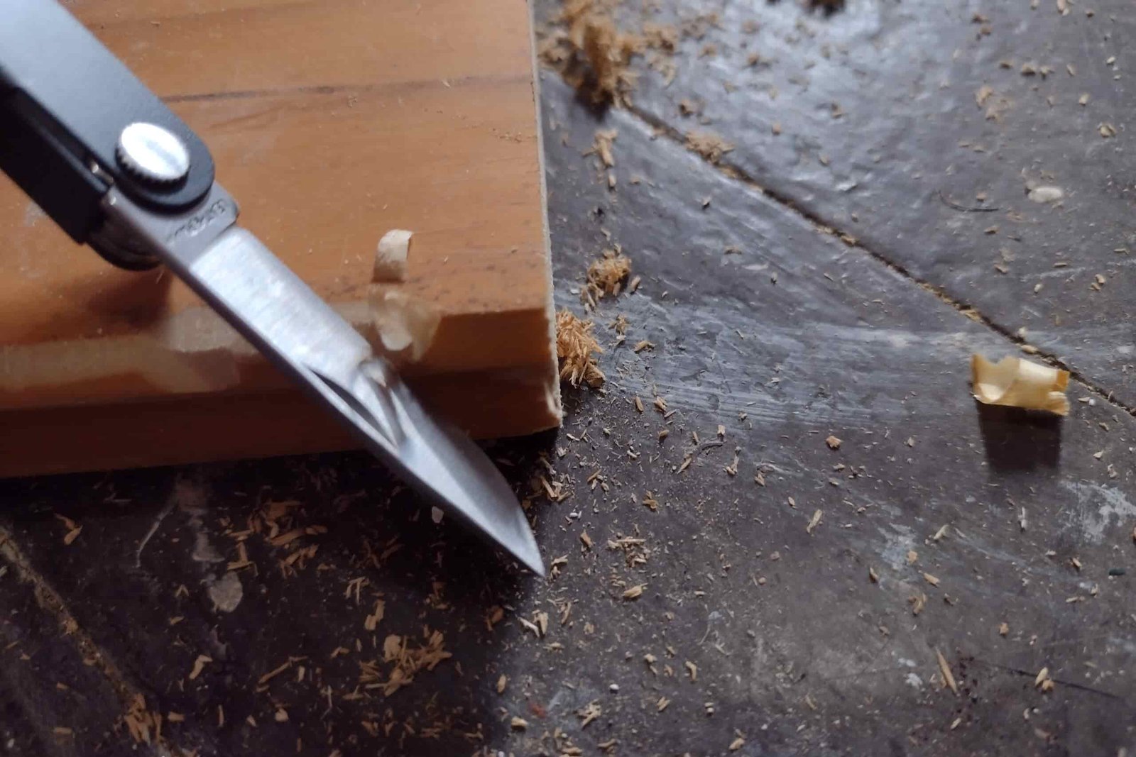 The Leatherman Micra is its blade extended and whittling wood shavings.