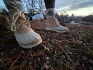 a woman wearing the sorel out-n-about IV's on bare ground