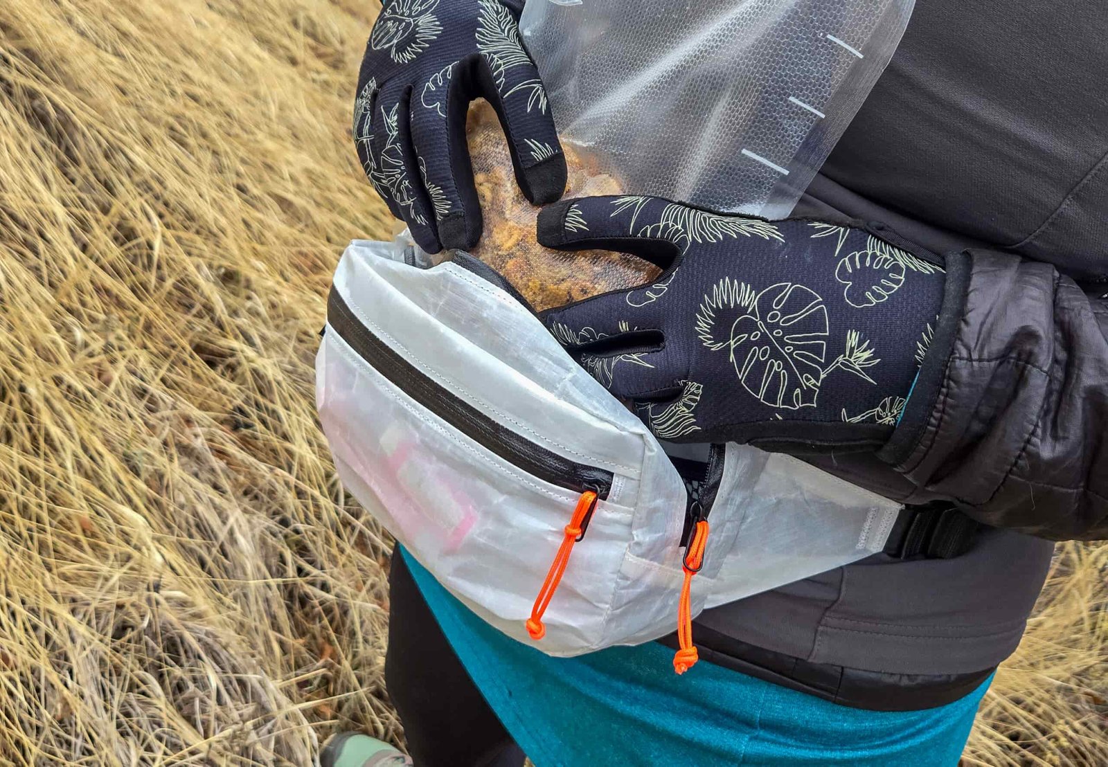 a woman stuffing items into the main compartment of the versa fanny pack