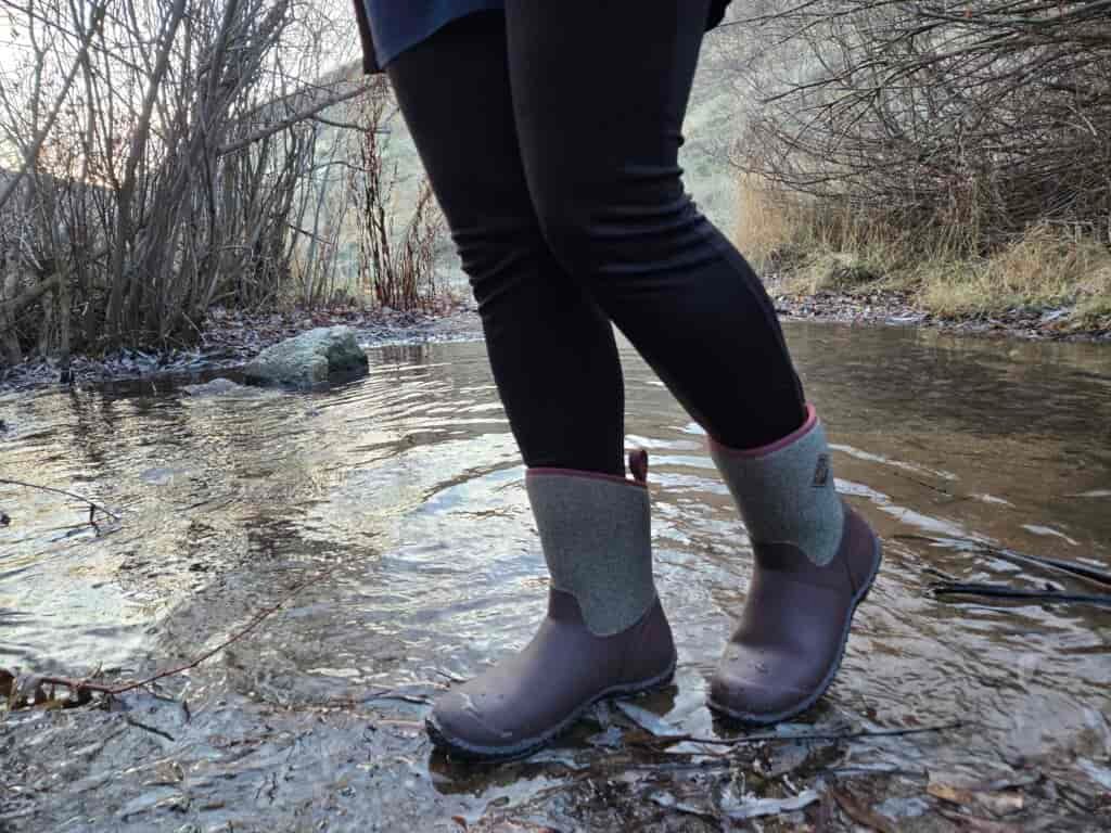 woman standing in a small stream in muck boots