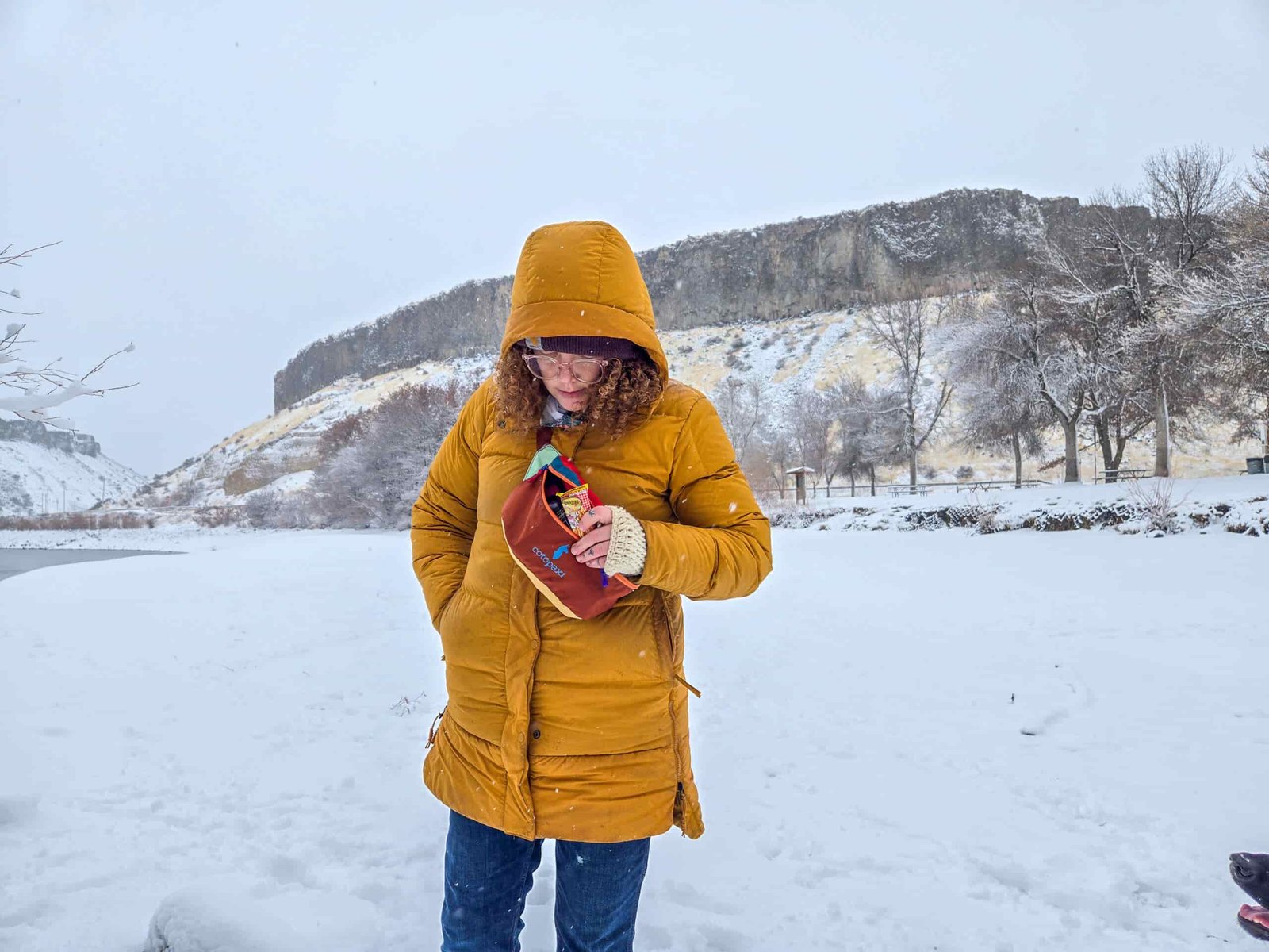 a woman a park with the cotopaxi bataan del dia slung over her shoulder