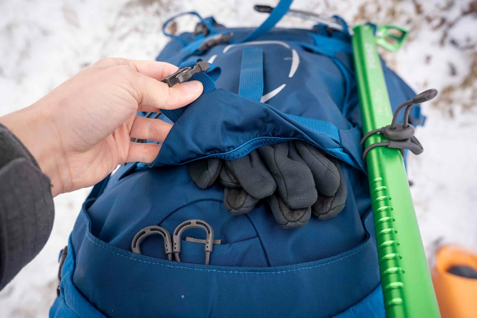 gloves stuffed in a front pocket of backpack