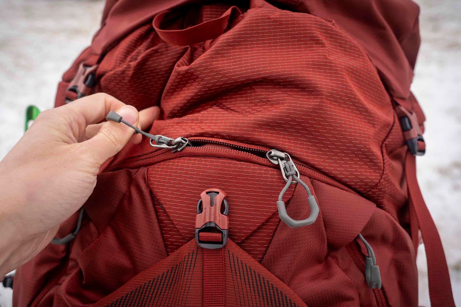 a hand holds a zipper on a backpack