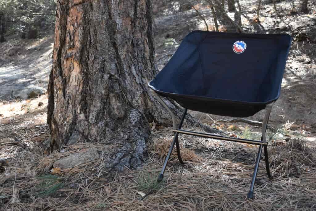 The Skyline Chair sits fully assembled next to the trunk of a lodgepole pine tree