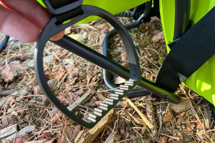 Detailed view of a foot stirrup with textured ridges attached to a child carrier frame.