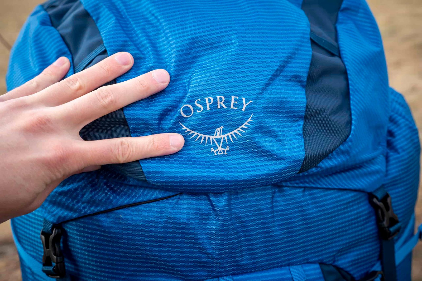 a hand holds the front of a backpack