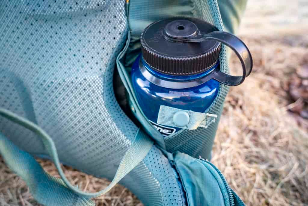a water bottle rests in a side pocket on a backpack