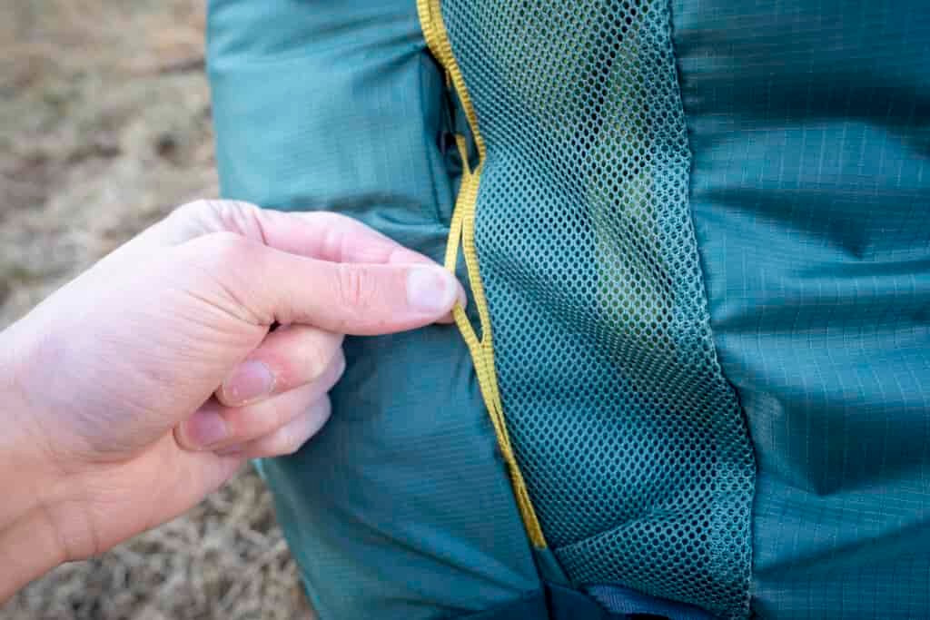 a hand holds a strap on a backpack