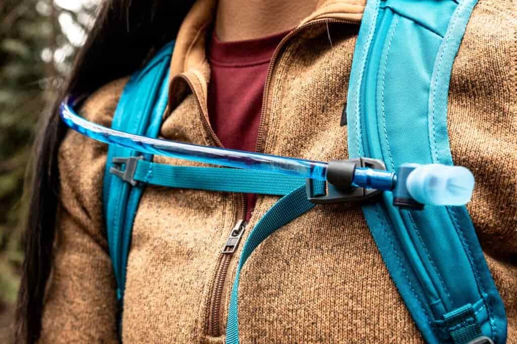 Details of Gregory Swift 16 H2O - a close up view of a person wearing the pack showing  the front straps and hydration hose
