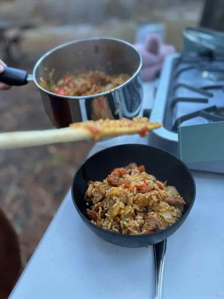 Blue camp stove at forested camp site making rice, burritos, and breakfast. 
