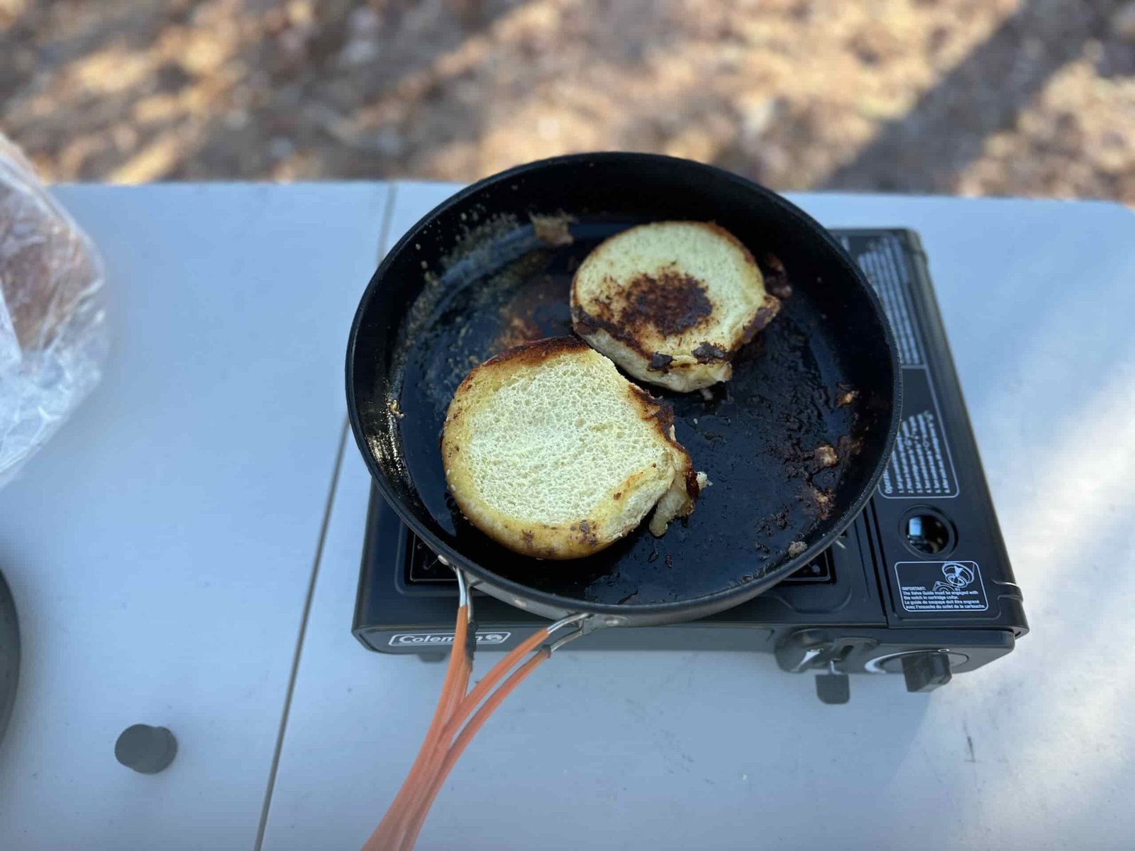 The Coleman Classic 1-Burner Butane Camping Stove cooking various meals at a campsite within the pines