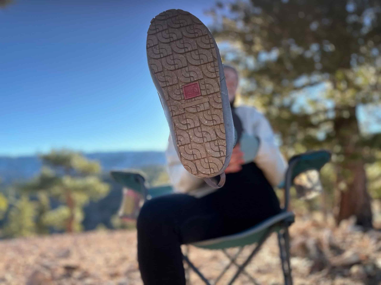 Woman at camp in high desert showing off the great traction on the soles of the North Face ThermoBall Traction Mules V