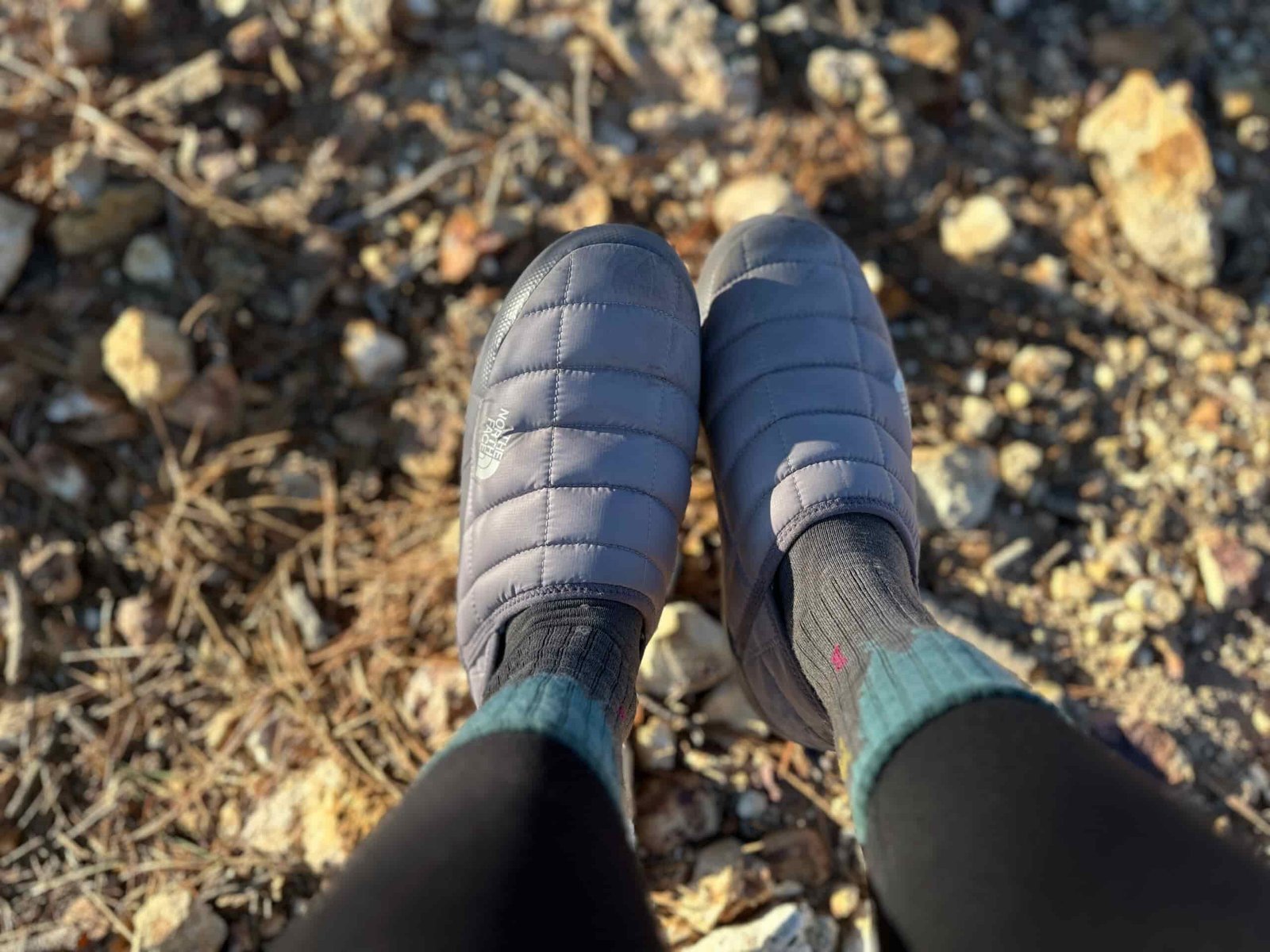 Women showing off North Face ThermoBall Traction Mules V on rocky, high desert camp site