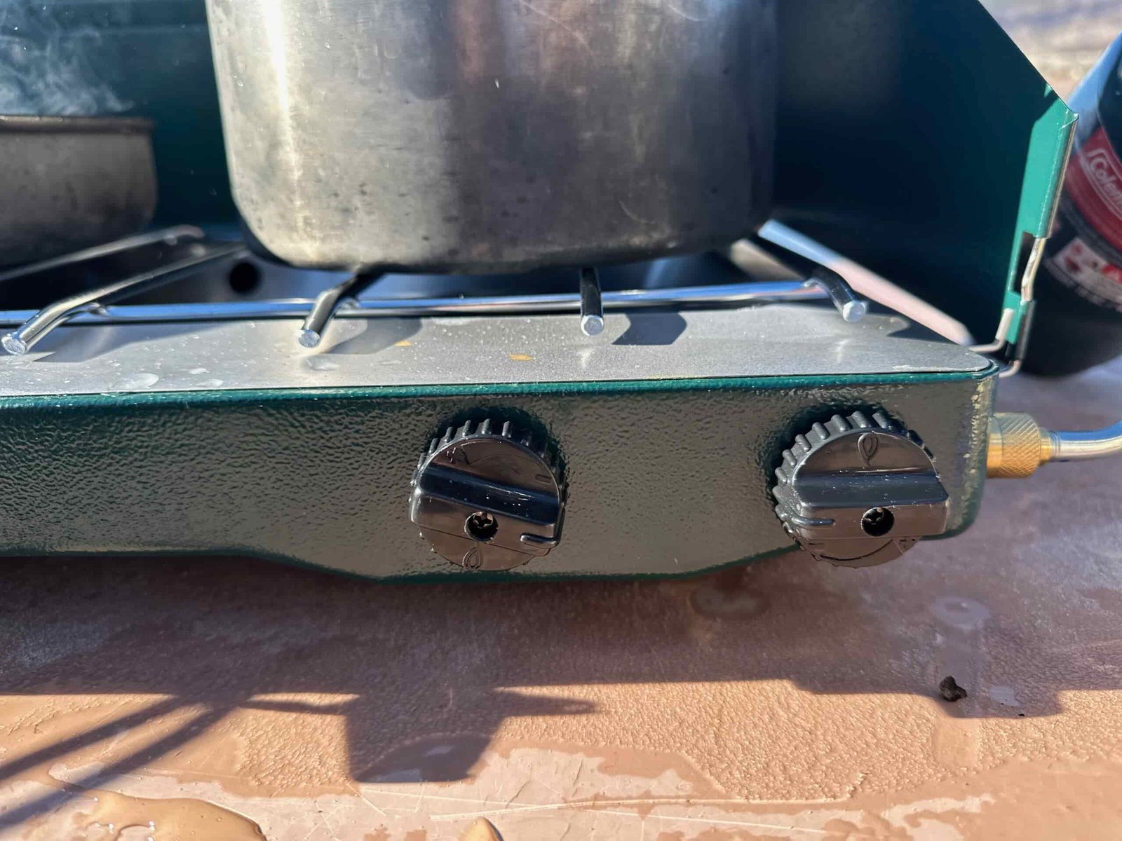 the Coleman Classic 2-Burner cooking camp meals at a beachside camp