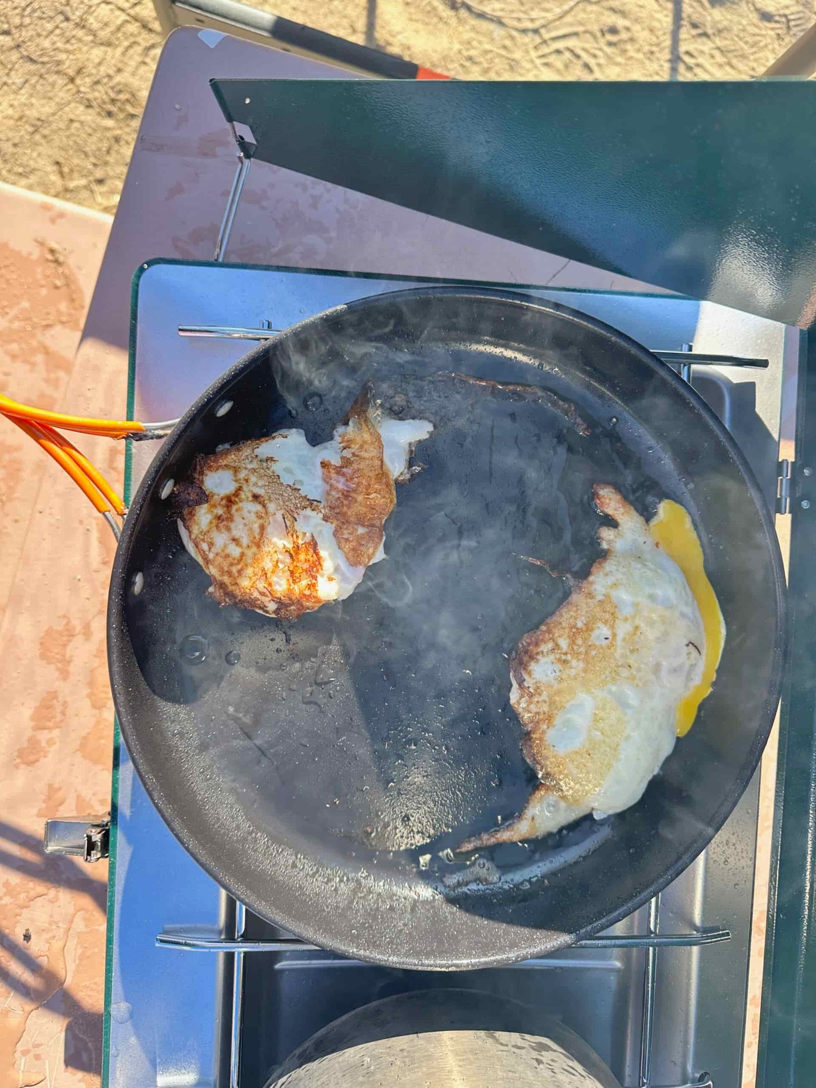 the Coleman Cascade Classic 2-Burner cooking camp meals at a beachside camp